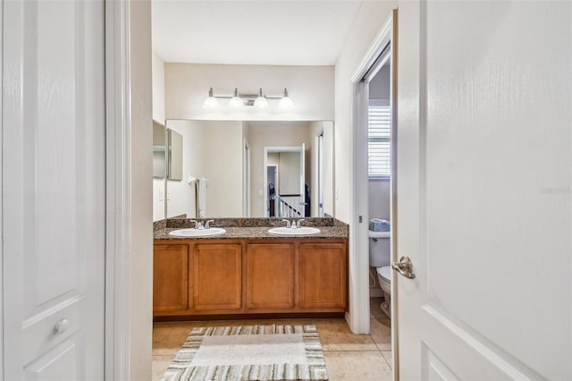 bathroom with double sink, tile flooring, toilet, and vanity with extensive cabinet space