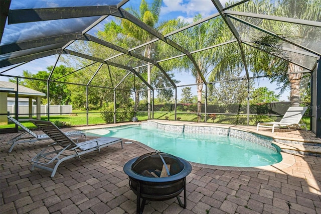 view of pool with glass enclosure, an outdoor fire pit, and a patio area