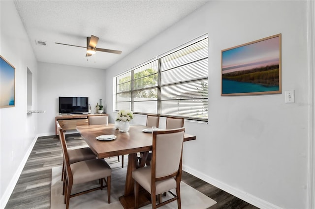 dining area with a textured ceiling, ceiling fan, and dark hardwood / wood-style flooring