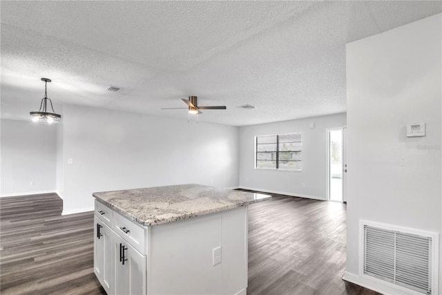 kitchen featuring light stone countertops, decorative light fixtures, white cabinetry, a textured ceiling, and dark hardwood / wood-style flooring