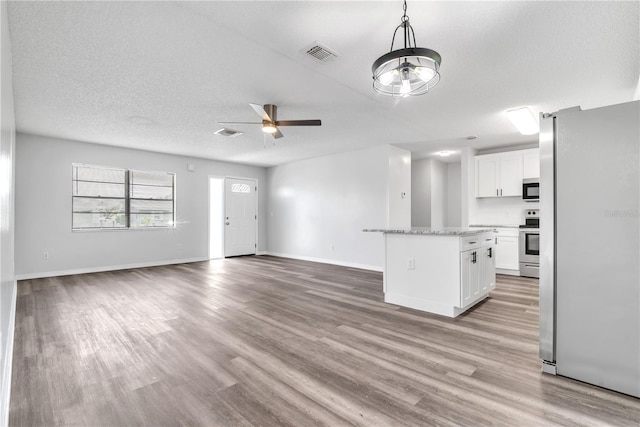 unfurnished living room with a textured ceiling, light wood-type flooring, and ceiling fan