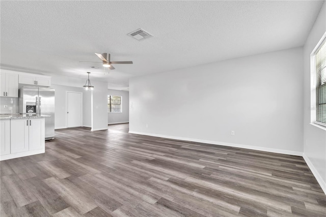 unfurnished living room with ceiling fan, a textured ceiling, and dark hardwood / wood-style flooring