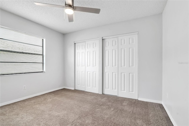 unfurnished bedroom featuring a textured ceiling, two closets, carpet, and ceiling fan