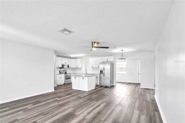 kitchen featuring a center island, white cabinetry, stainless steel appliances, pendant lighting, and dark wood-type flooring