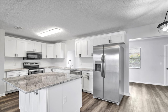 kitchen featuring dark hardwood / wood-style flooring, appliances with stainless steel finishes, a center island, and white cabinets