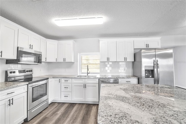 kitchen featuring sink, stainless steel appliances, white cabinets, dark wood-type flooring, and decorative backsplash