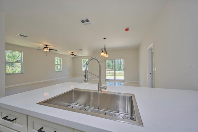 kitchen featuring ceiling fan, hanging light fixtures, white cabinets, and sink