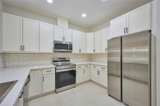 kitchen with white cabinetry, backsplash, appliances with stainless steel finishes, sink, and light tile floors