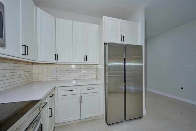 kitchen with light tile flooring, stainless steel fridge, white cabinetry, and tasteful backsplash