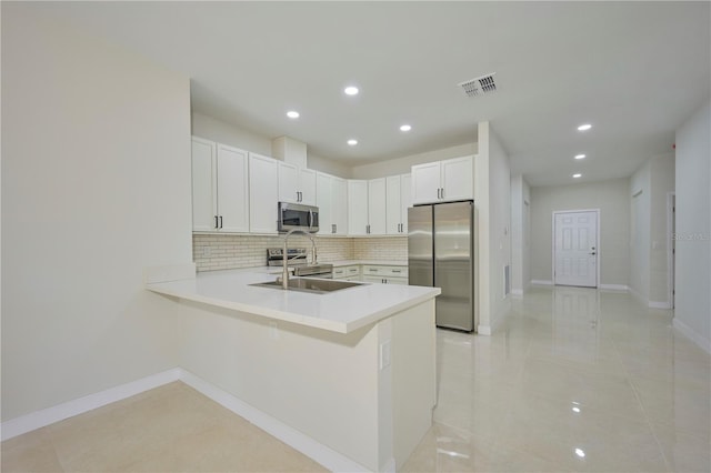 kitchen featuring light tile floors, backsplash, white cabinetry, stainless steel appliances, and kitchen peninsula