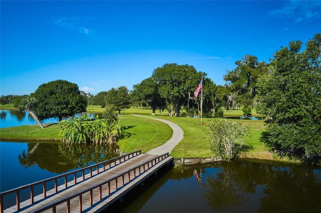 view of dock with a lawn and a water view