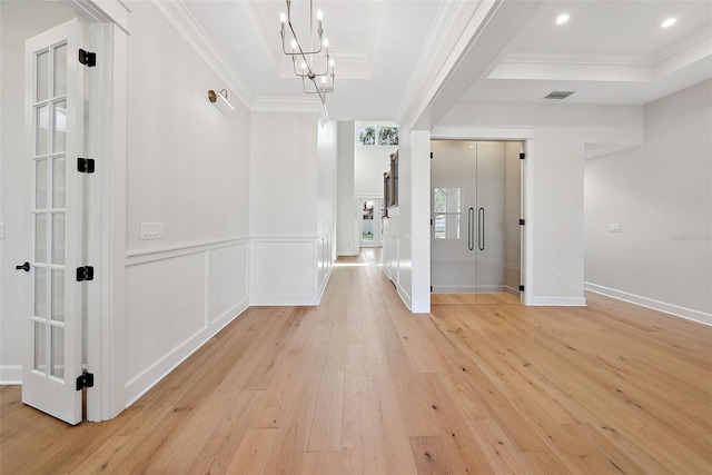 corridor with crown molding, a notable chandelier, and light hardwood / wood-style floors