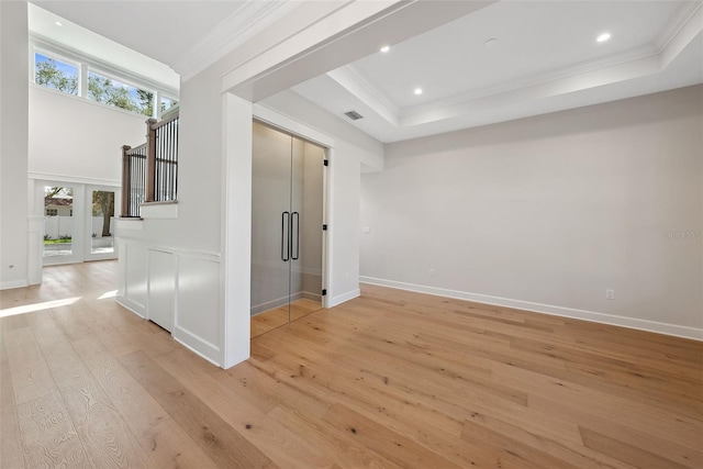 spare room with french doors, crown molding, light wood-type flooring, and a tray ceiling