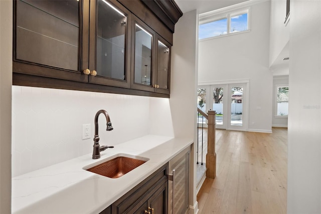 bar featuring light stone countertops, dark brown cabinets, and light hardwood / wood-style flooring