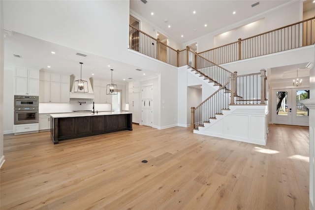 kitchen with crown molding, light hardwood / wood-style flooring, and a large island with sink