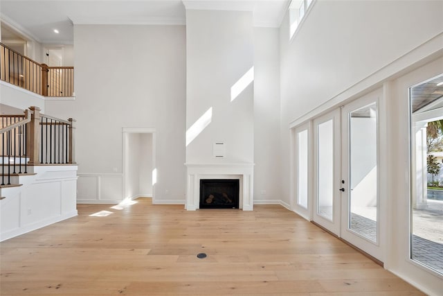 unfurnished living room with crown molding, light hardwood / wood-style floors, and french doors