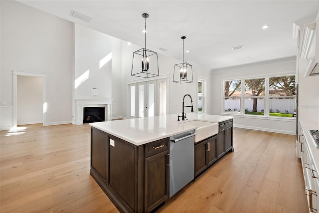 kitchen with sink, dark brown cabinets, light wood-type flooring, appliances with stainless steel finishes, and pendant lighting