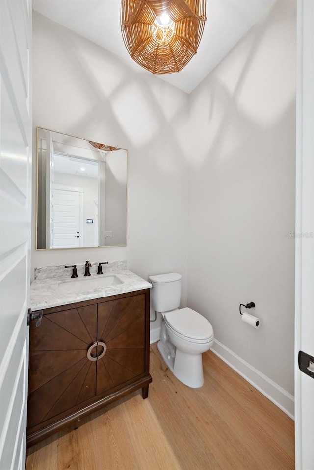 bathroom with wood-type flooring, vanity, and toilet