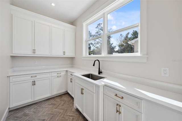 kitchen featuring dark parquet flooring, sink, and white cabinets