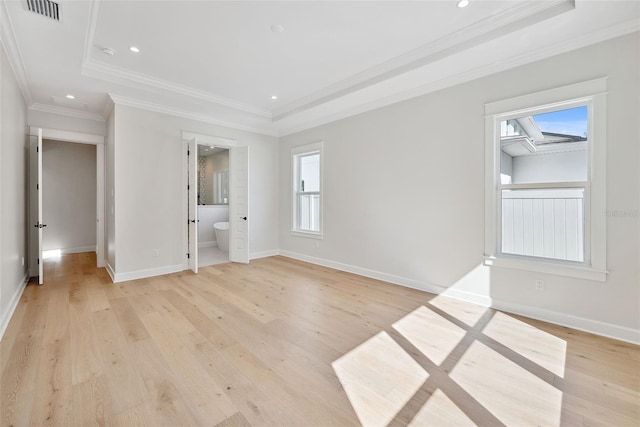 unfurnished room with a tray ceiling, crown molding, and light wood-type flooring