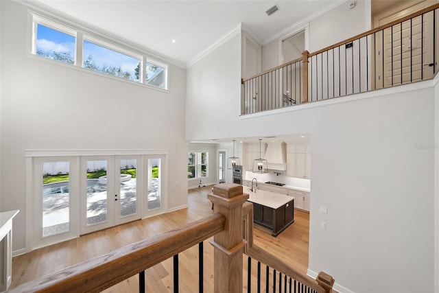 staircase with crown molding, a towering ceiling, wood-type flooring, and french doors