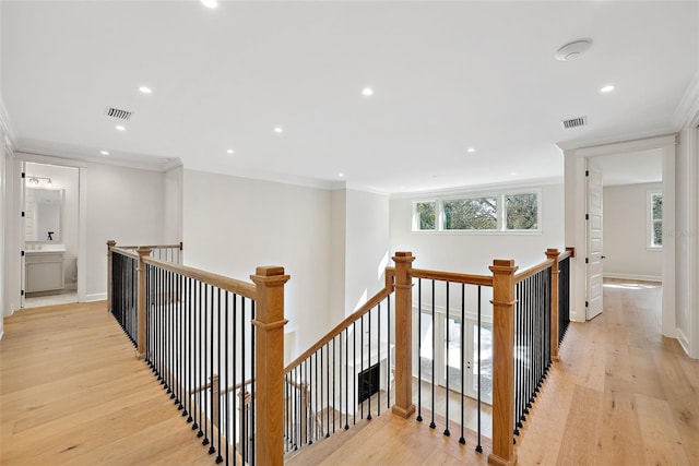 hallway featuring ornamental molding and light hardwood / wood-style floors