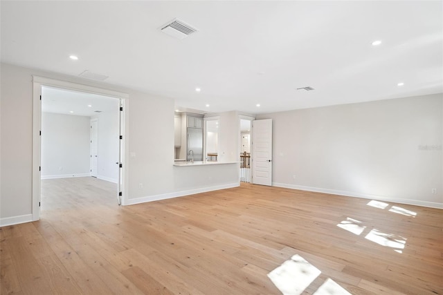 unfurnished living room with sink and light hardwood / wood-style floors