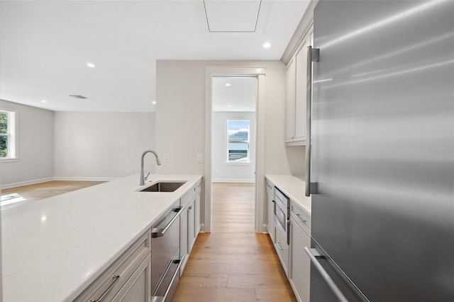 kitchen featuring appliances with stainless steel finishes, sink, white cabinets, and light wood-type flooring