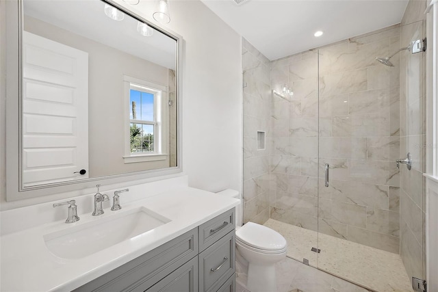 bathroom with a shower with door, vanity, and toilet
