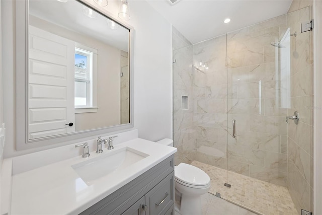 bathroom with a shower with door, vanity, and toilet