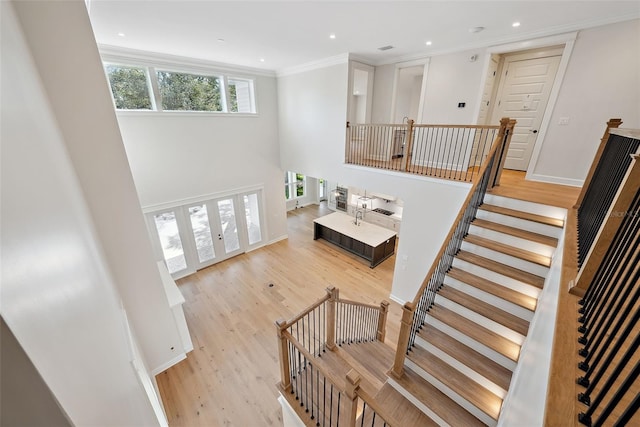 stairs with ornamental molding, a towering ceiling, hardwood / wood-style floors, and french doors