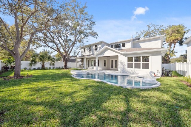 back of house with a fenced in pool and a lawn