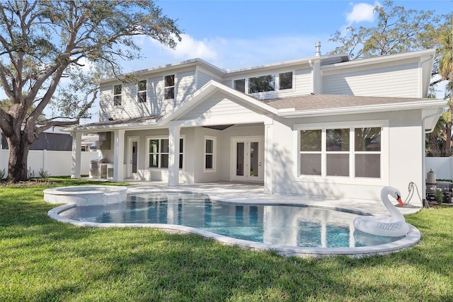 rear view of house featuring french doors, a swimming pool with hot tub, a yard, and a patio area