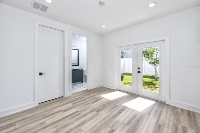 spare room with french doors and light hardwood / wood-style flooring