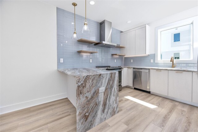 kitchen with stainless steel appliances, wall chimney range hood, pendant lighting, light hardwood / wood-style flooring, and white cabinetry