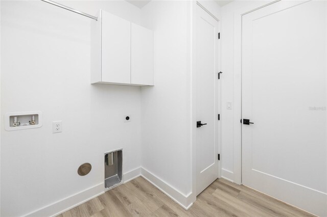 clothes washing area with electric dryer hookup, cabinets, light hardwood / wood-style flooring, and washer hookup