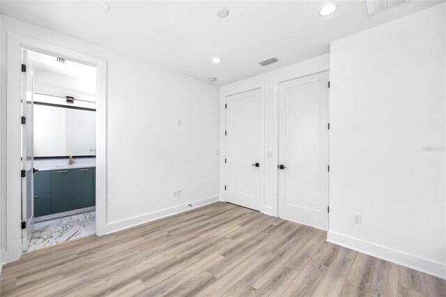 unfurnished bedroom with connected bathroom and light hardwood / wood-style floors