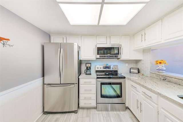 kitchen featuring appliances with stainless steel finishes, tasteful backsplash, white cabinetry, and light stone countertops