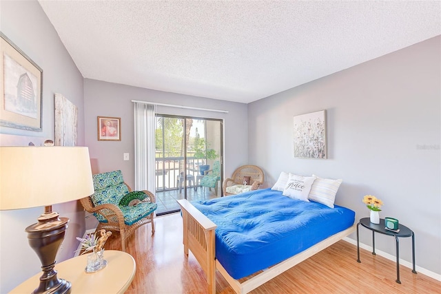 bedroom with a textured ceiling, light wood-type flooring, and access to outside