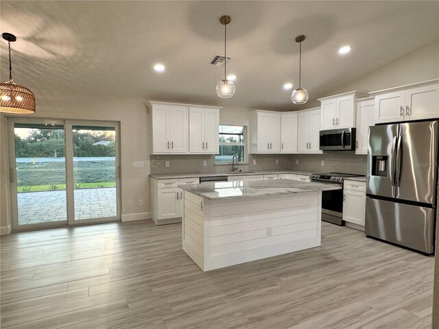 kitchen with appliances with stainless steel finishes, white cabinetry, and hanging light fixtures