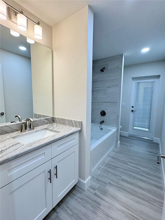 bathroom featuring a textured ceiling, vanity, and tiled shower / bath