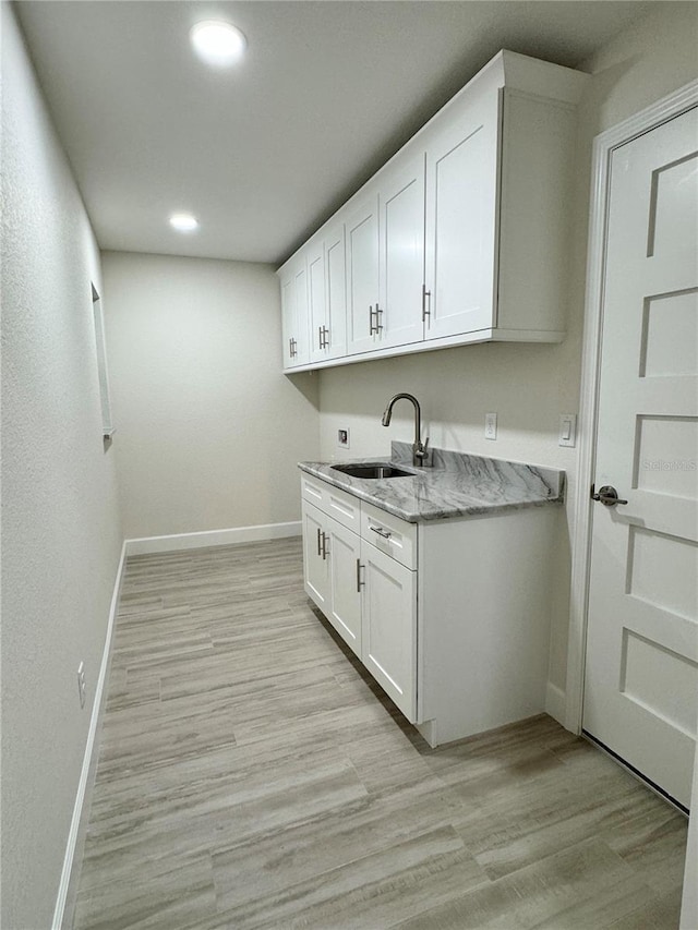 kitchen with sink, light hardwood / wood-style floors, and white cabinets