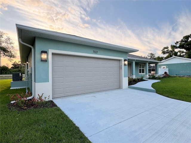 view of front of property with central AC, a lawn, and a garage