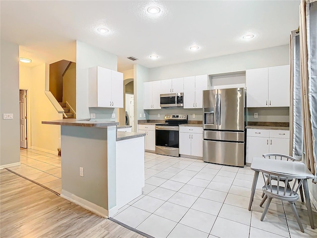 kitchen featuring appliances with stainless steel finishes, light wood-type flooring, and white cabinets