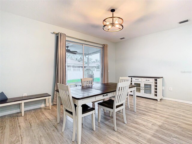 dining room featuring ceiling fan with notable chandelier and light hardwood / wood-style floors