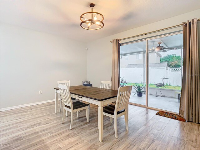 dining area with light hardwood / wood-style flooring and ceiling fan with notable chandelier