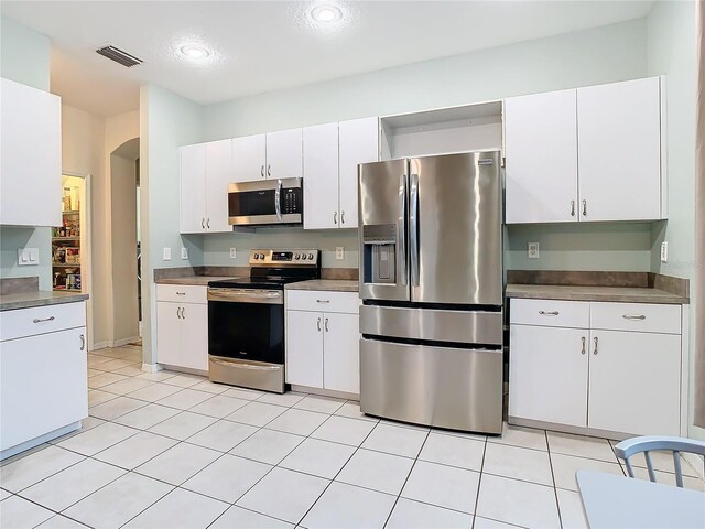 kitchen with white cabinets, appliances with stainless steel finishes, and light tile floors