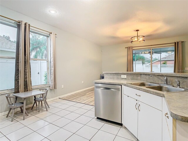 kitchen featuring light tile floors, sink, dishwasher, white cabinetry, and hanging light fixtures