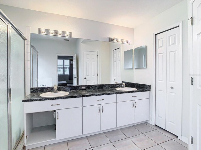 bathroom with vanity with extensive cabinet space, double sink, and tile flooring