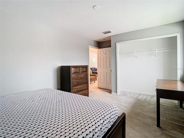 bedroom with a closet, a textured ceiling, and light colored carpet